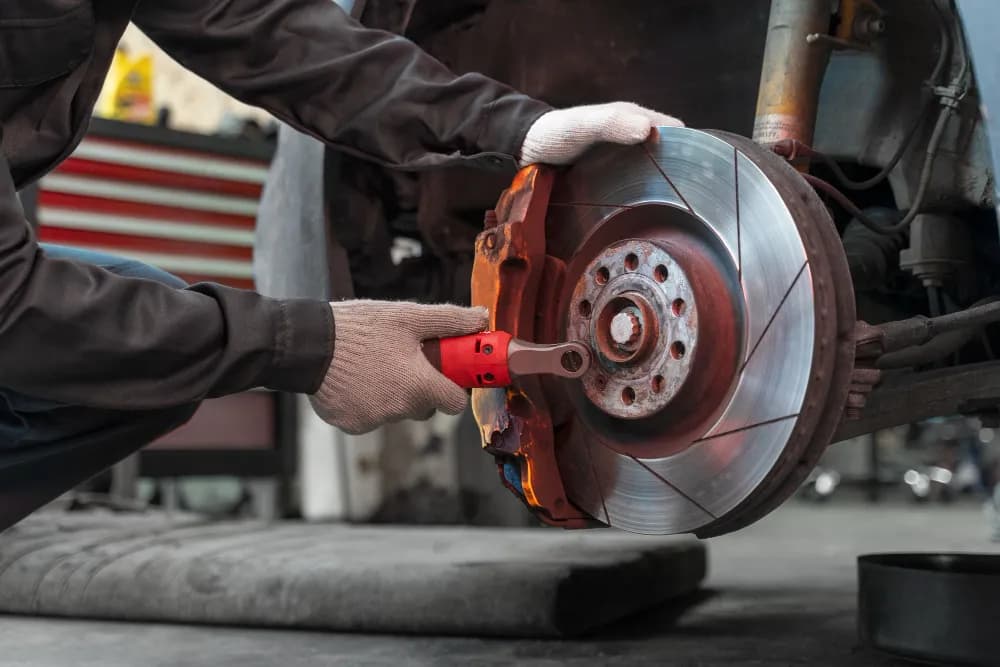 Technician inspecting car brake system in Dubai workshop